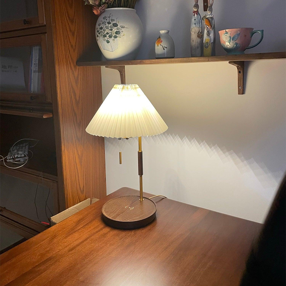 Glowing lamp with a brown wood base and gold-tone stem beneath a wood shelf of ceramic objects