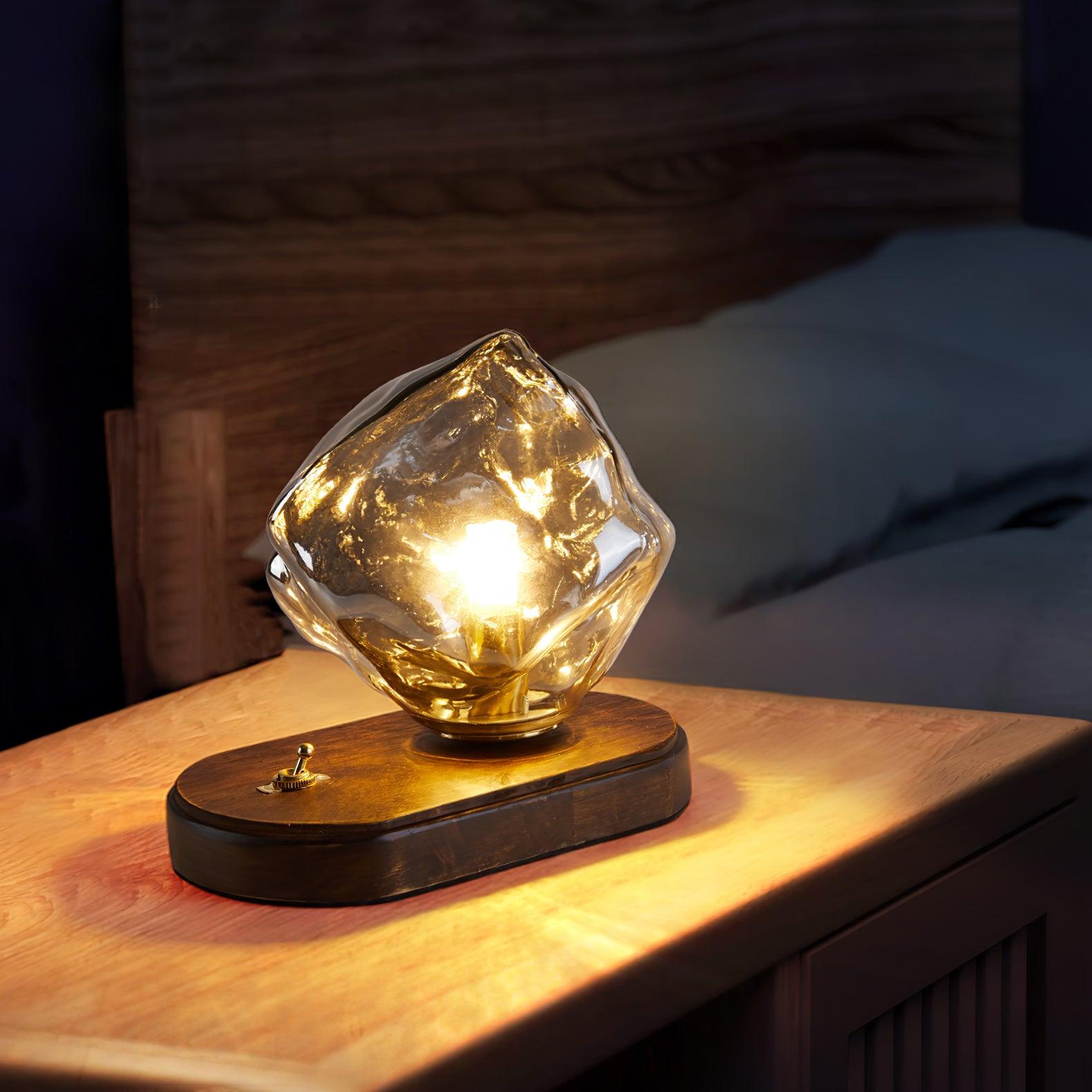 Ice Stone lamp with an oval wood base beside a wood headboard and dark blue pillow