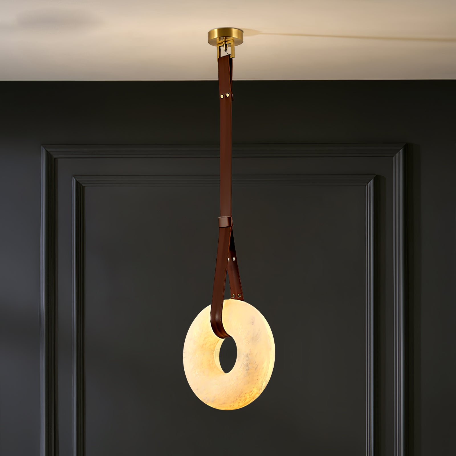 Vertical glowing ring with brown strap and gold ceiling fitting in a room corner.