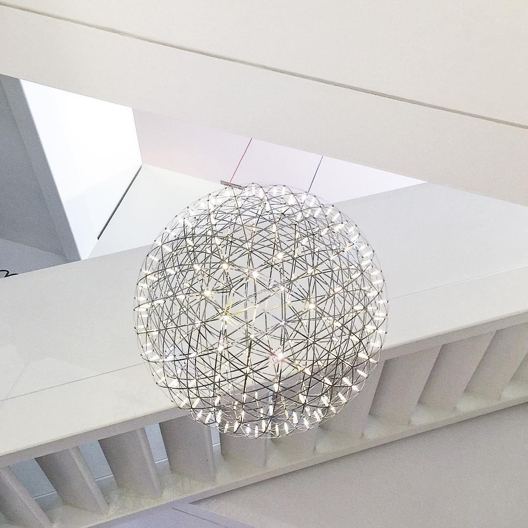 Single lit sphere beneath geometric skylight beams with thin upper suspension lines