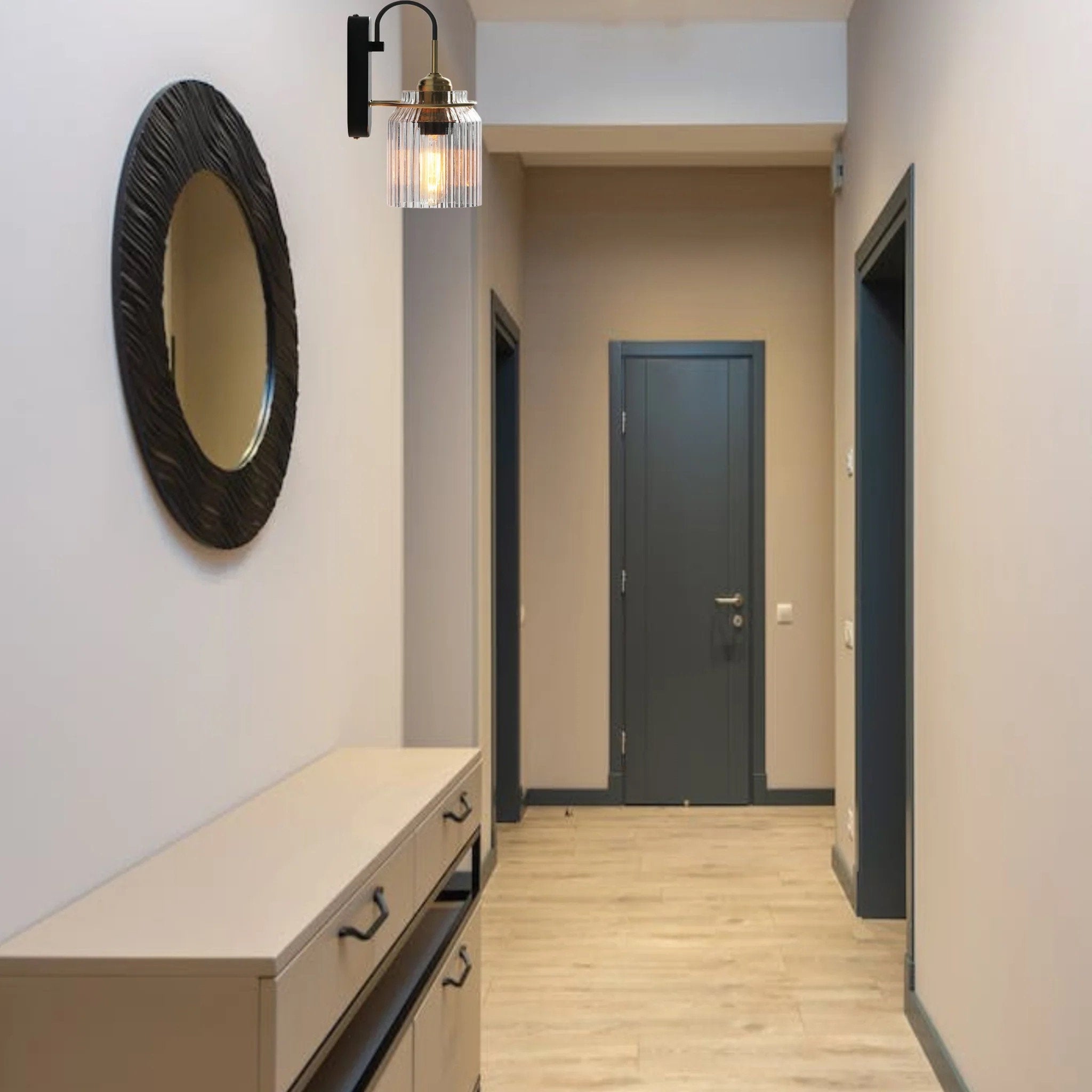Industria wall sconce beside an oval black-framed mirror and pale console in a hallway with blue-gray doors