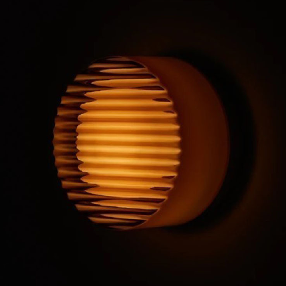 Angled orange light in a dark setting, showing its ribbed face, short cylindrical body and rear plate