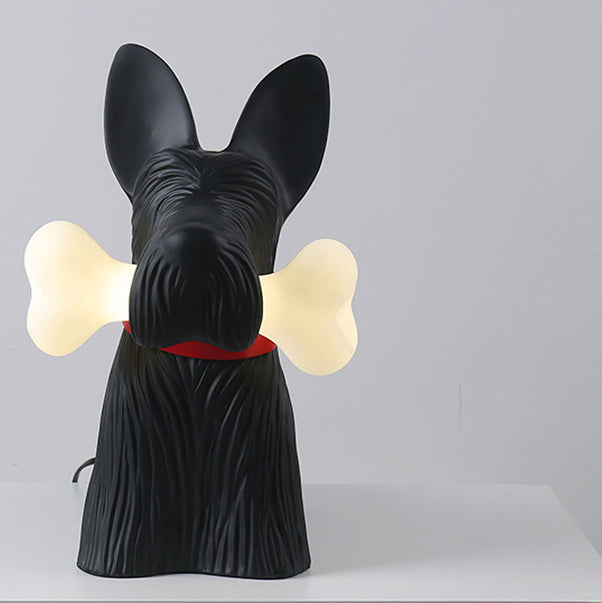 Front view of the black dog lamp with upright ears, red collar and glowing bone ends beside its muzzle