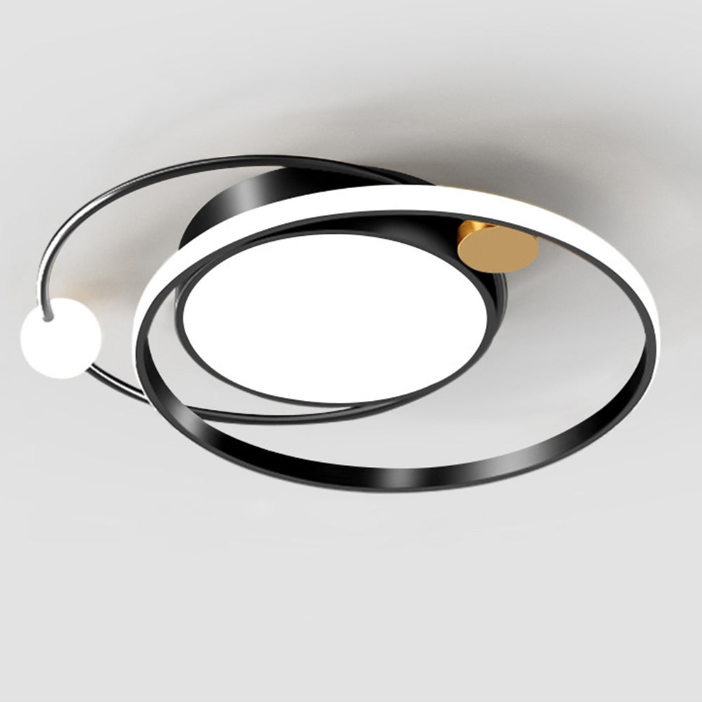 Black orbital ceiling fixture against a pale ceiling with central disk, luminous ring and gold-tone connector