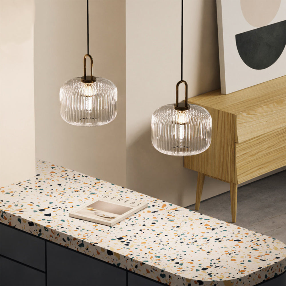 Two wide clear ribbed glass pendants near a wooden sideboard and speckled bench