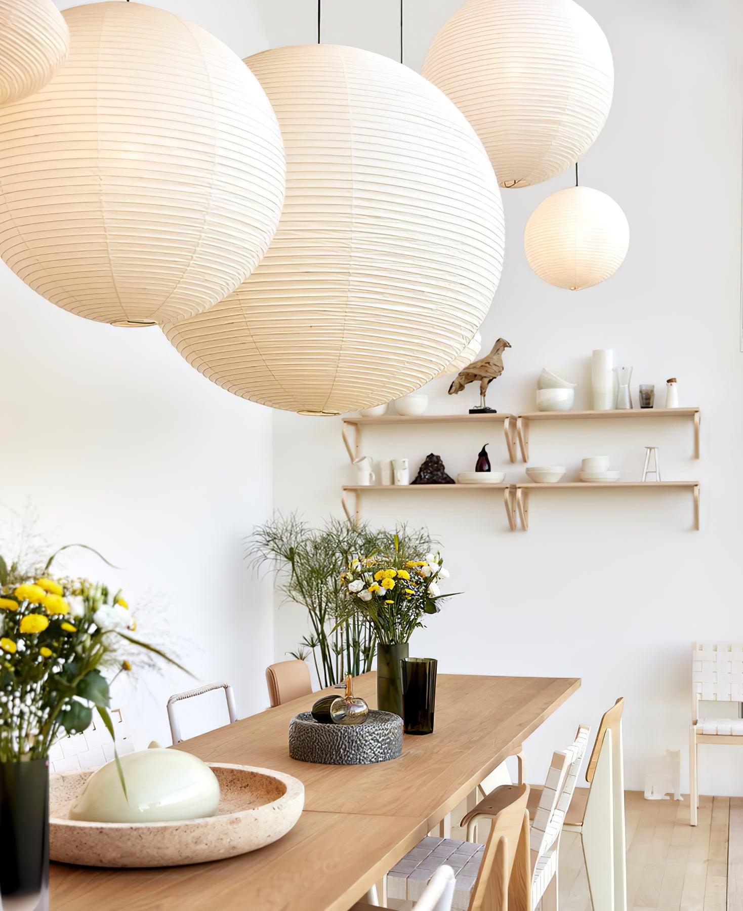 Group of White globes above a flower vase and wood dining table with woven chairs and ceramics shelf
