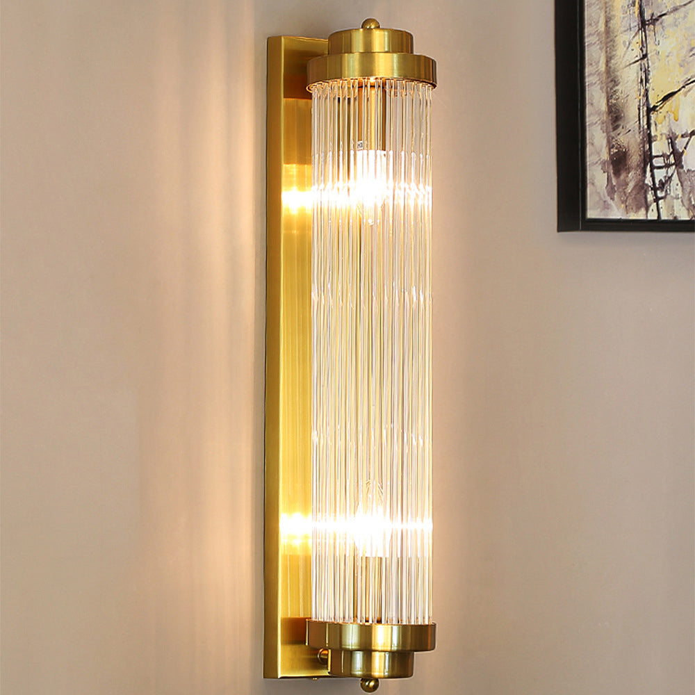 Gold Crystal Pillar wall light glowing on a beige wall beside framed abstract artwork