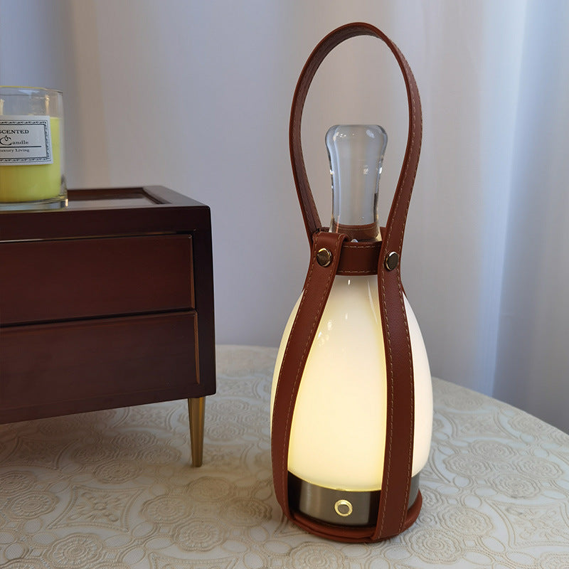 Close Bell lamp view with oval brown handle and round base detail beside a wooden drawer unit and candle jar