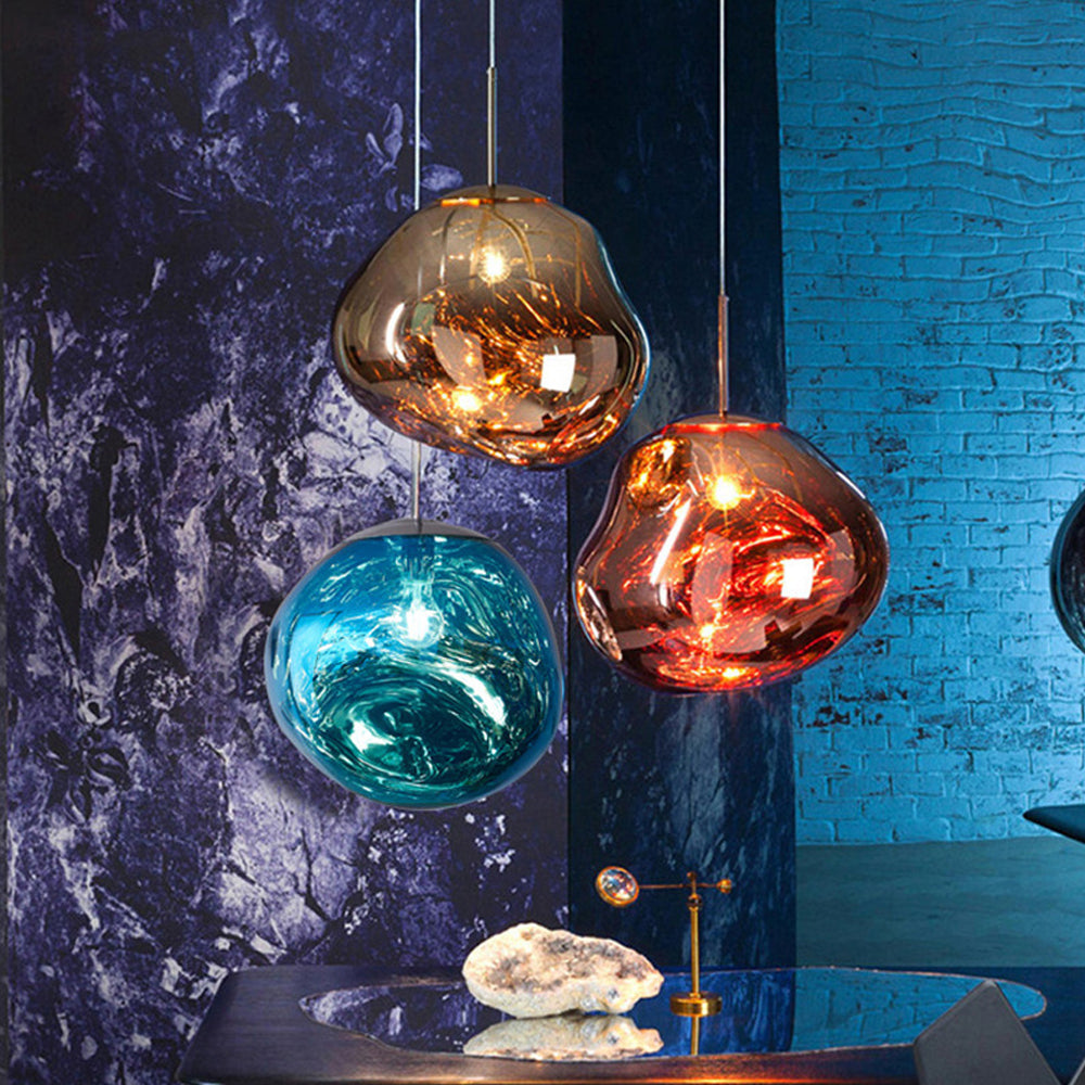 Glowing Gold, Rose Gold and Blue irregular shades in front of blue brickwork above a round glass table