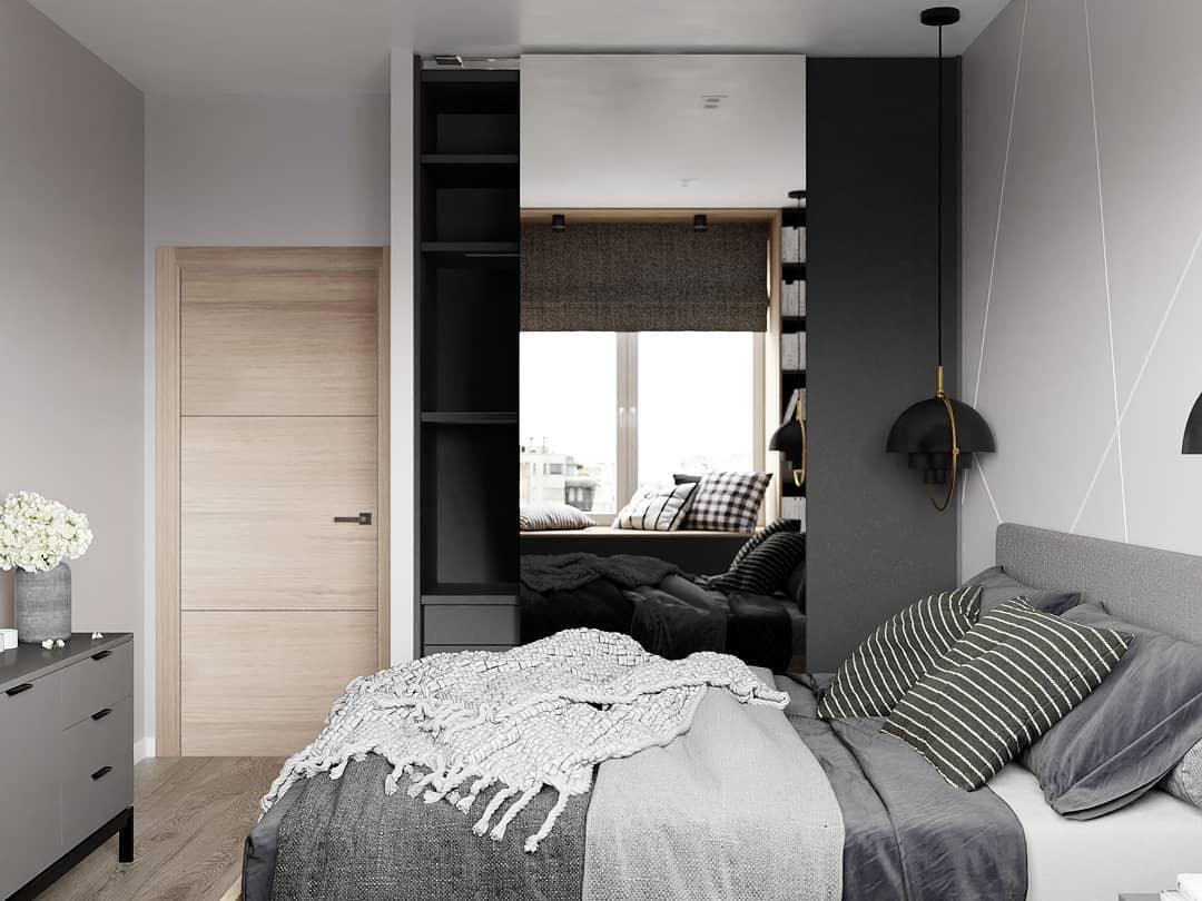 Black pendant at the side of a bed beneath a dark window blind.
