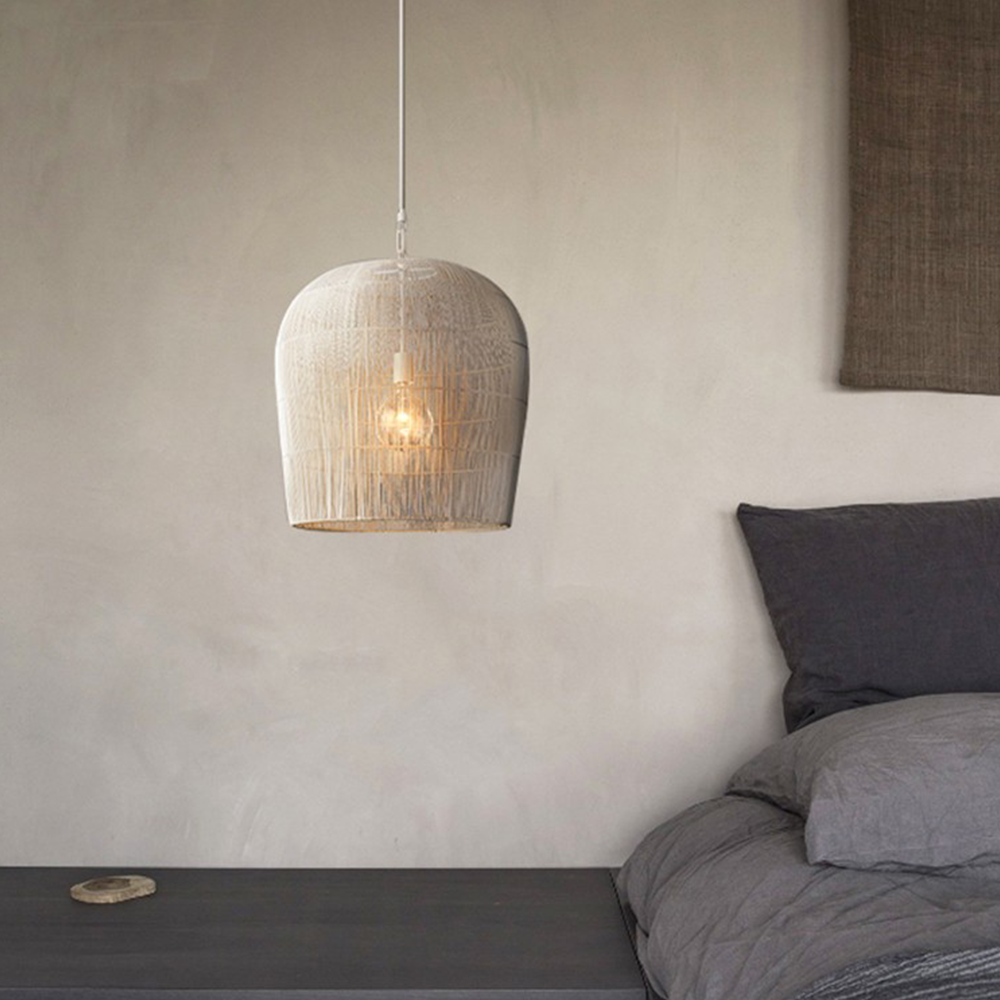 White rattan pendant beside a bed and low table