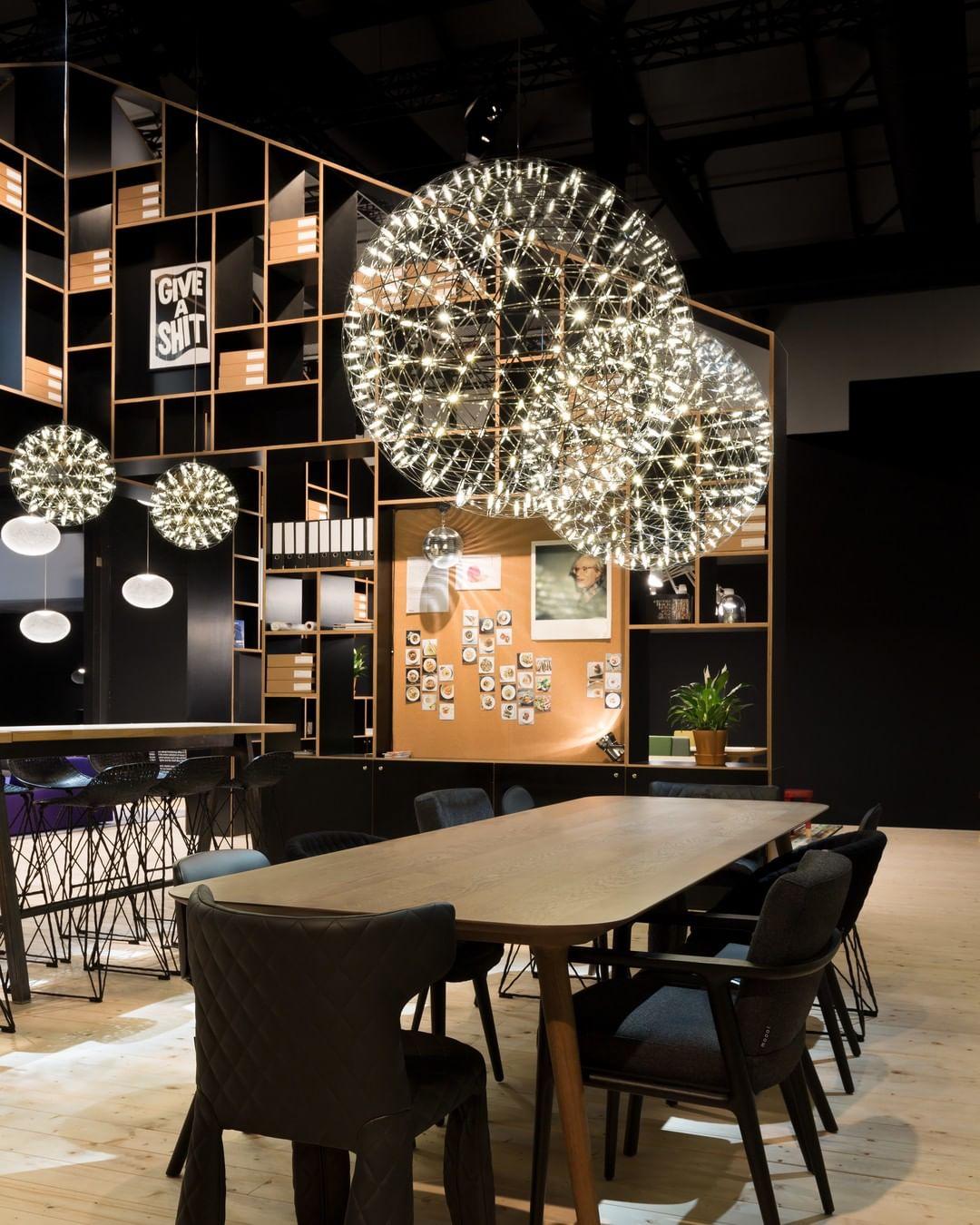Large and small glowing globes above wood tables in a dark display room