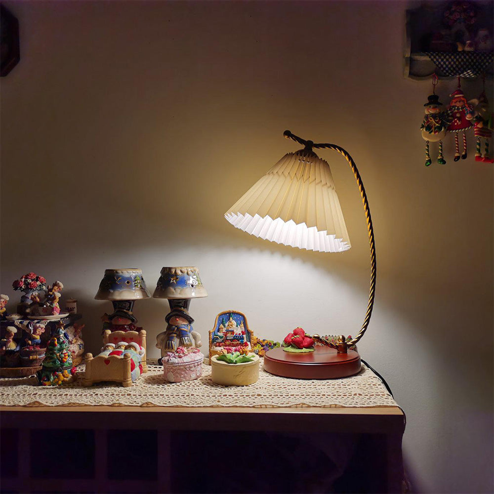 Lit pale pleated lamp on a lace-covered cabinet beside a collection of small figurines