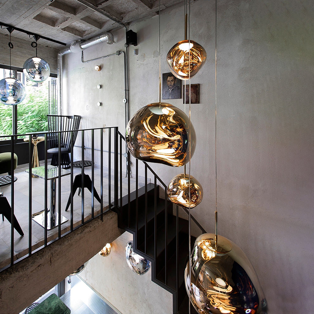Gold irregular pendants in an open stairwell with black railings, concrete ceiling and a wooden chair