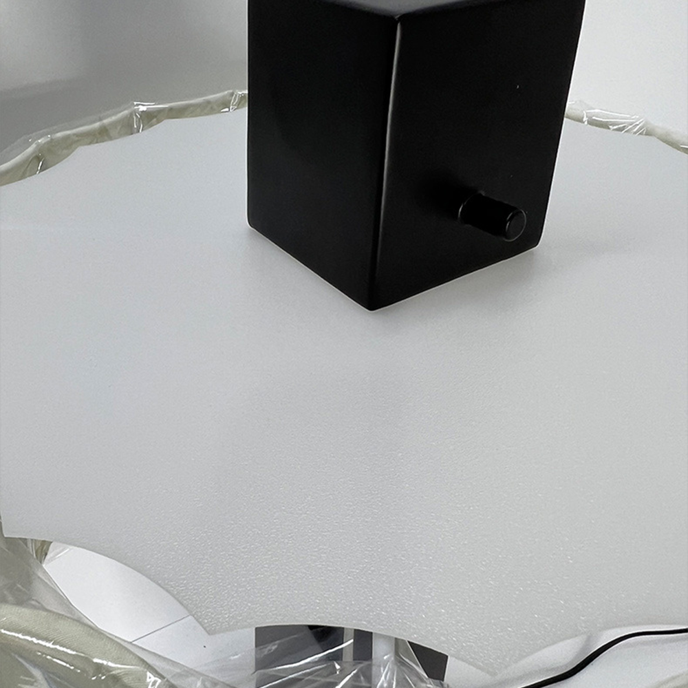 Close-up of the tapered black lamp base with a cylindrical side knob and nearby cable