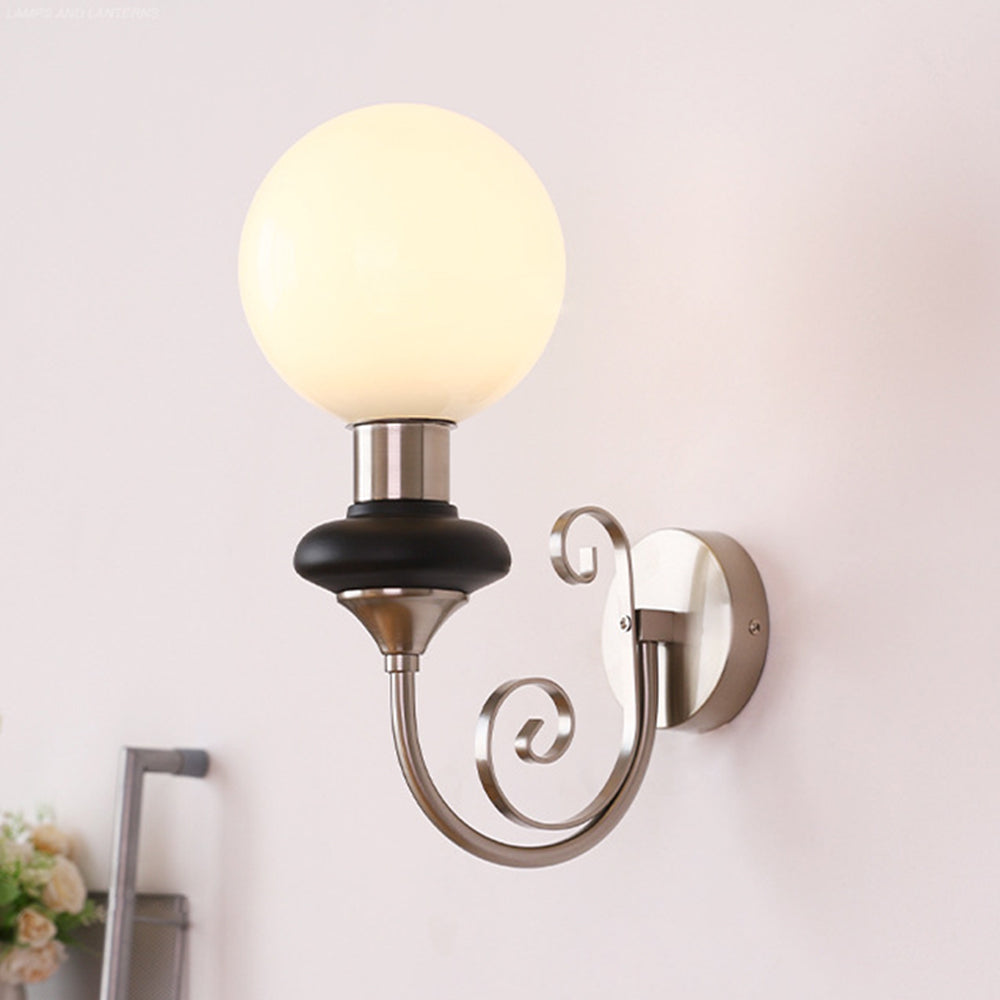 Illuminated chrome-and-black globe sconce by flowers