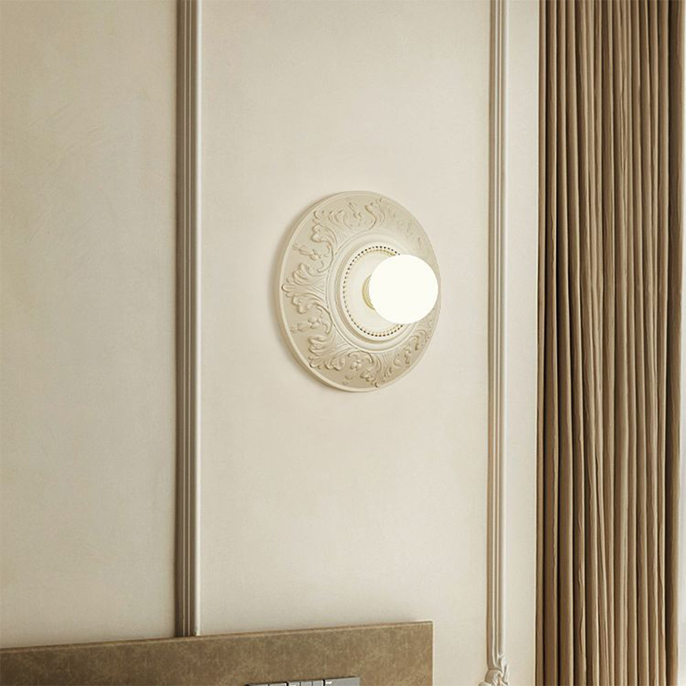 Closer bedside view of cream relief medallion and glowing globe beside a brown curtain