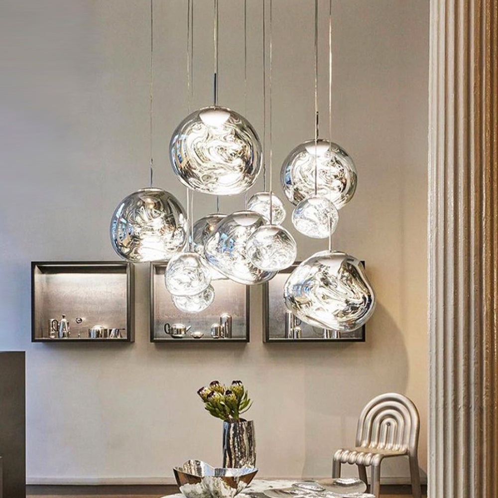 Silver irregular pendants beside framed object displays, bronze curtains and a metallic vase of flowers
