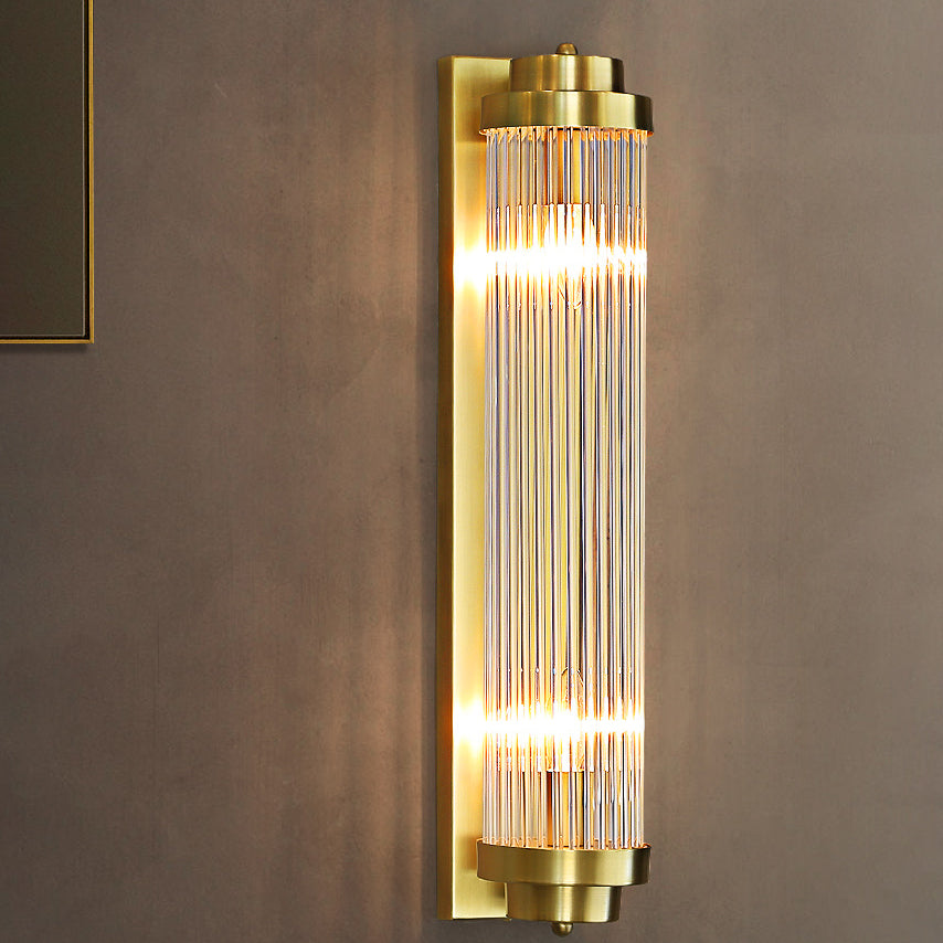 Lit Gold rod wall light on a grey wall near a black-and-gold picture frame