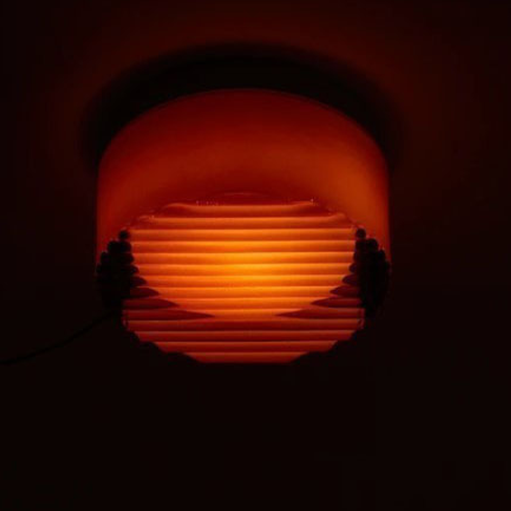 Orange round ribbed light glowing against a dark background, with a cord visible at the edge