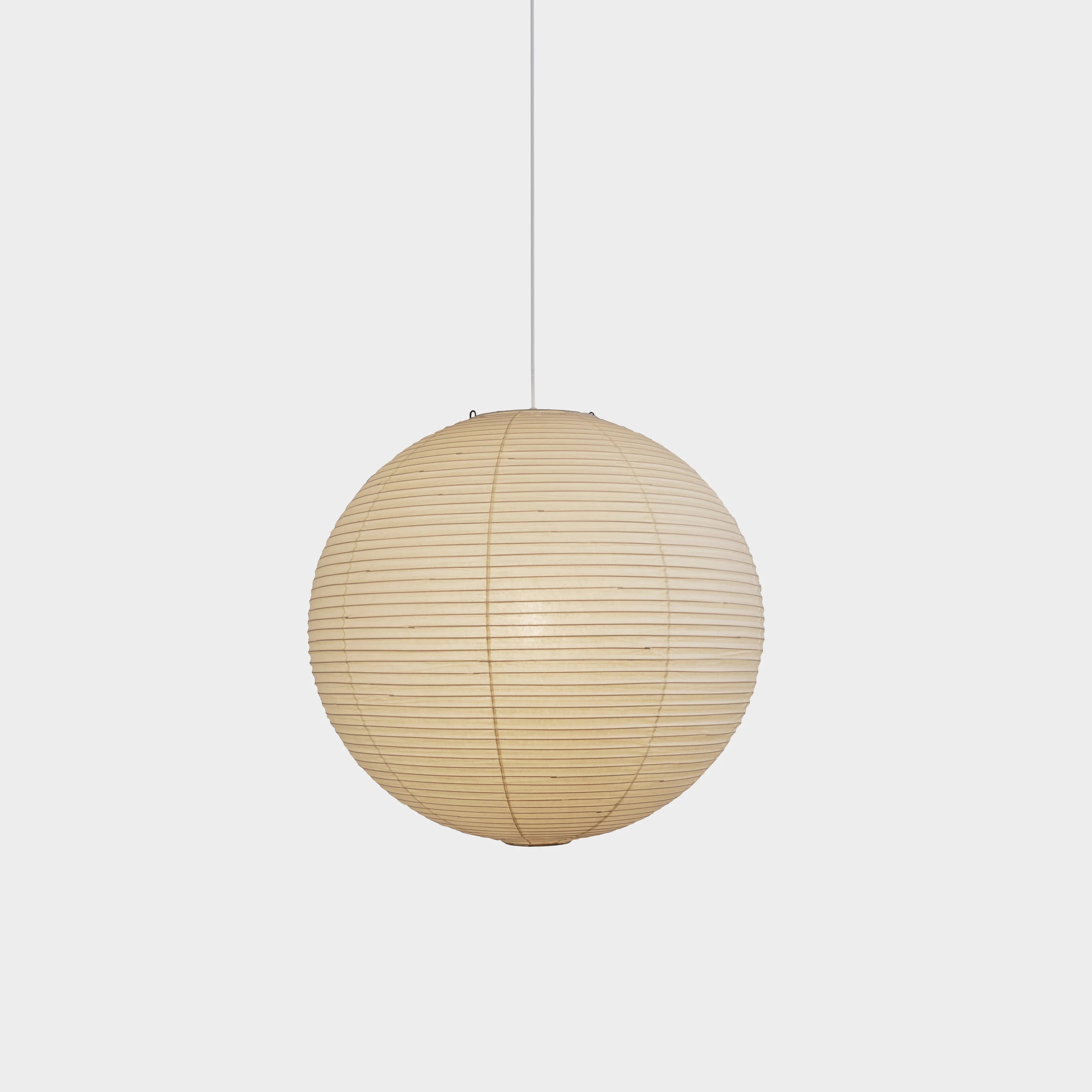 White ribbed paper globe glowing against a white background with a white hanging cord