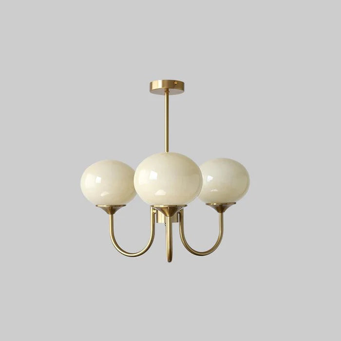 Three beige glass globes on gold-tone curved arms and rod against a plain background