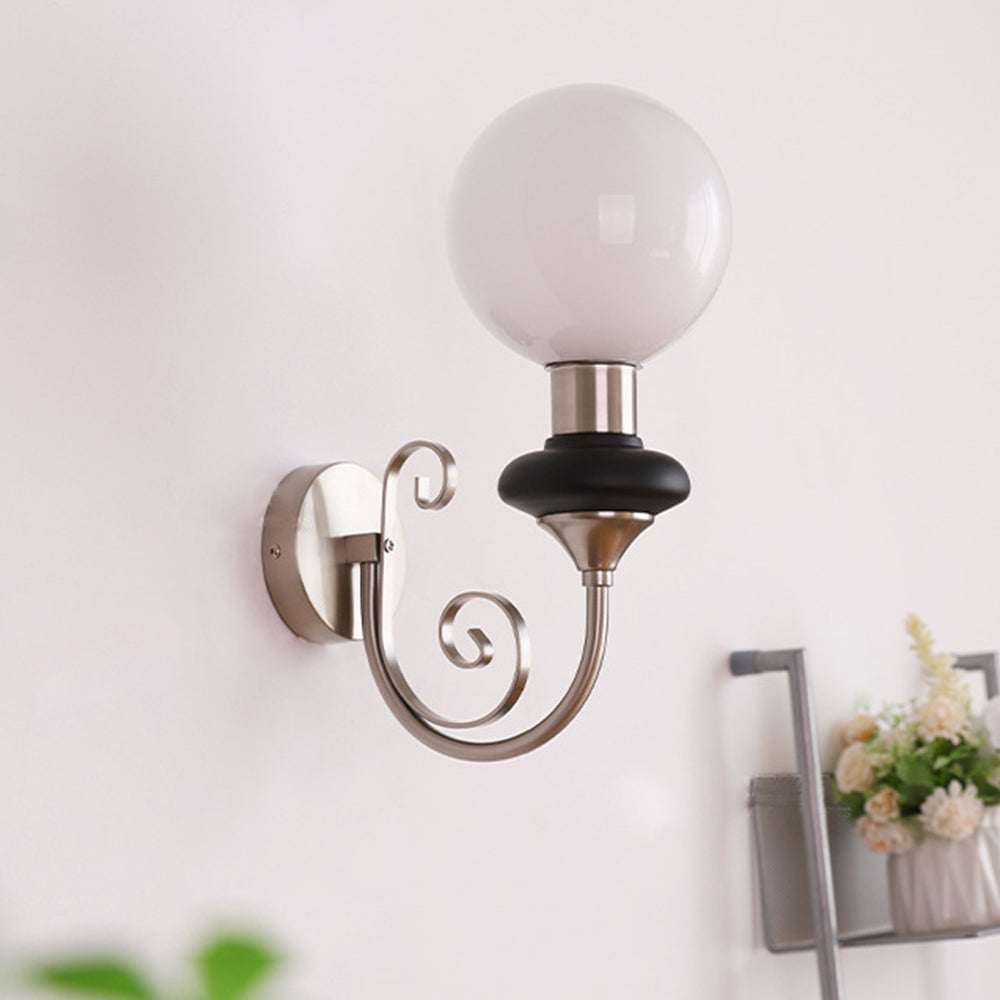 Unlit chrome-and-black globe sconce beside flowers