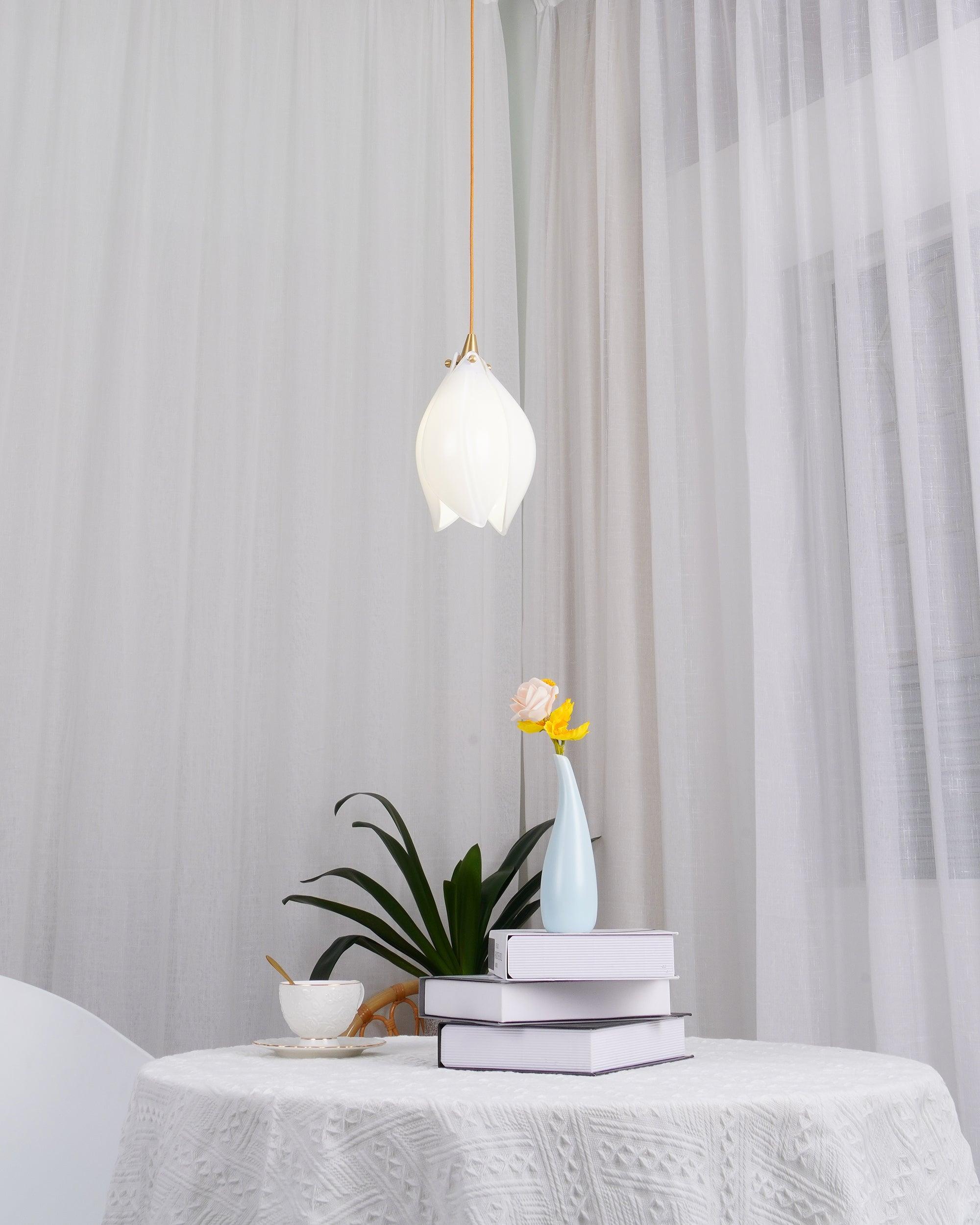 Single glowing flower pendant above a cloth-covered table with a blue flower vase