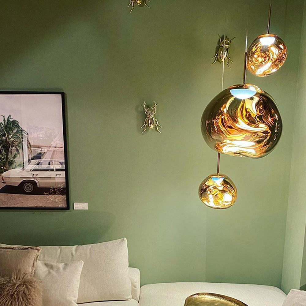 Three Gold irregular shades against a sage green wall with decorative beetles and car artwork above a white sofa