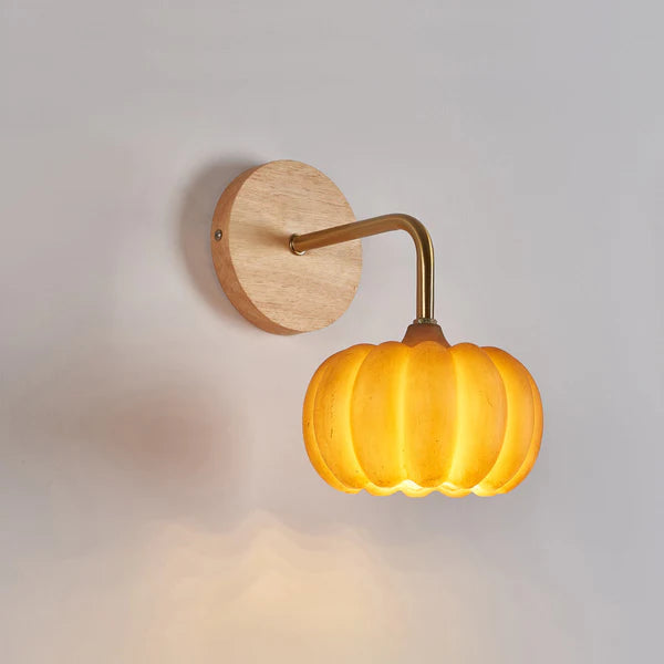 Close view of the glowing ribbed pumpkin shade, bent arm and wood-grain-looking round plate