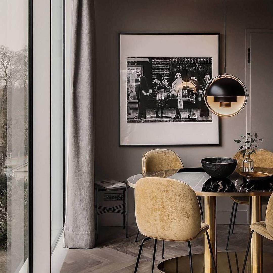 Black-and-gold dome pendant near framed artwork above a small dining table.