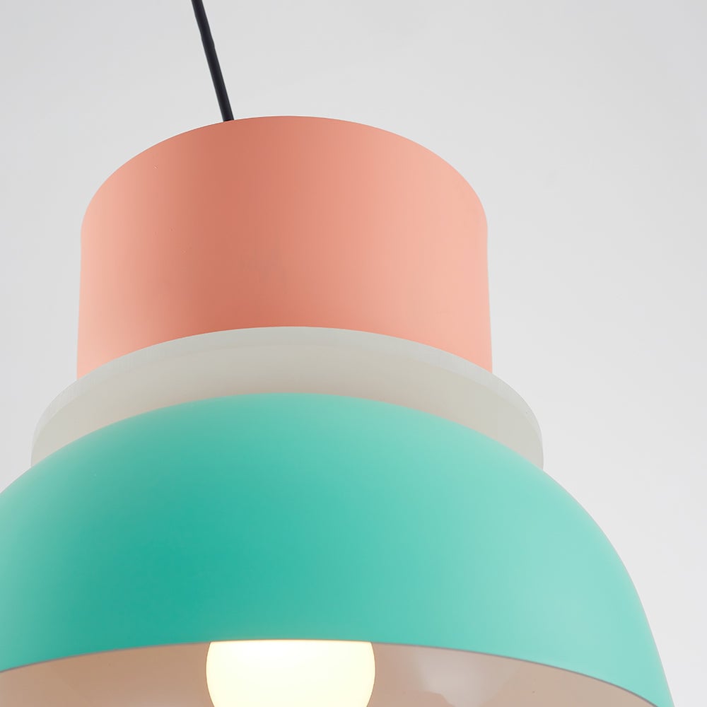 Low-angle detail of the pink-green pendant with a glowing bulb visible beneath the green shade