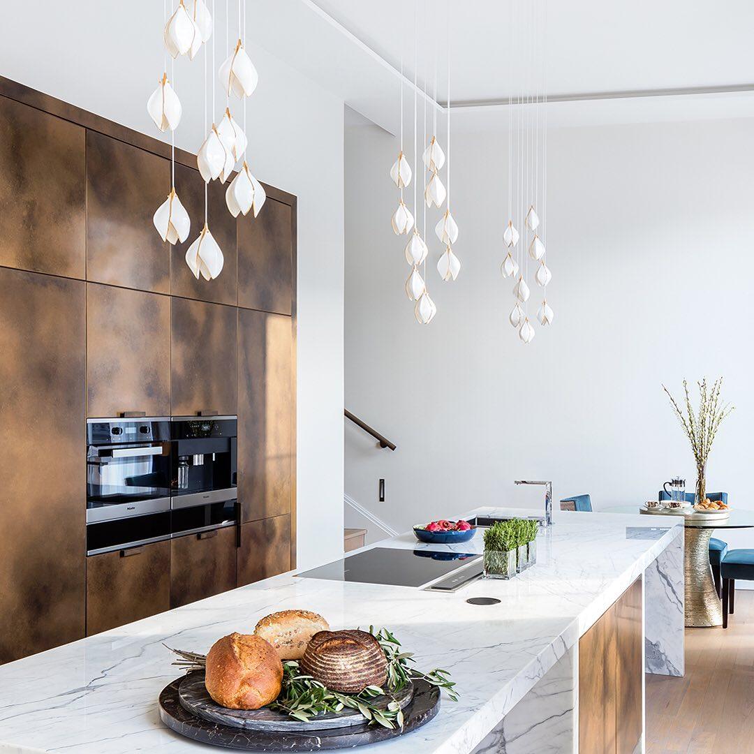Petal clusters above a veined kitchen island beside brown cabinets and a staircase