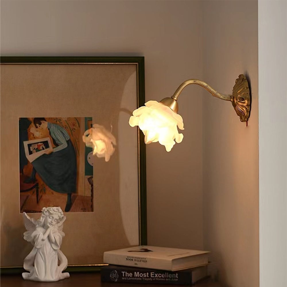 Petal wall light beside reflective framed art, books and a white angel figure