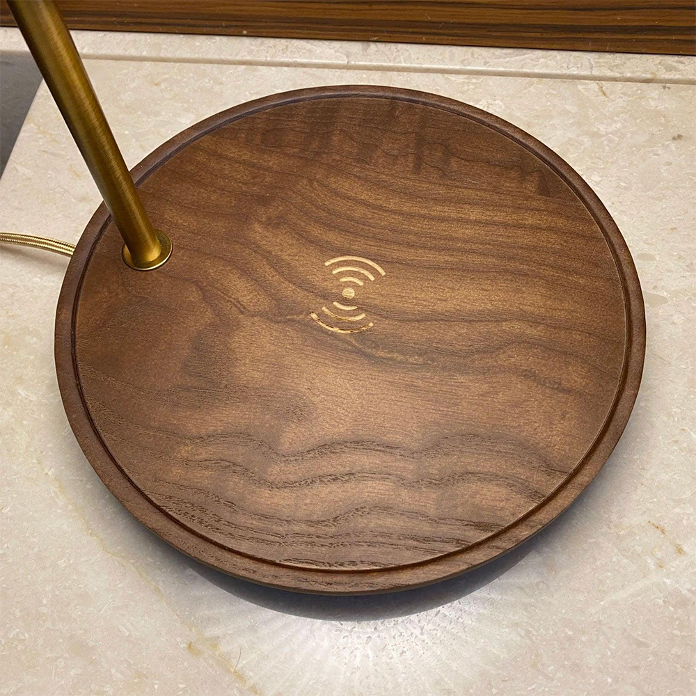 Dark brown round wood-grain lamp base with a charging symbol and gold-tone stem viewed from above