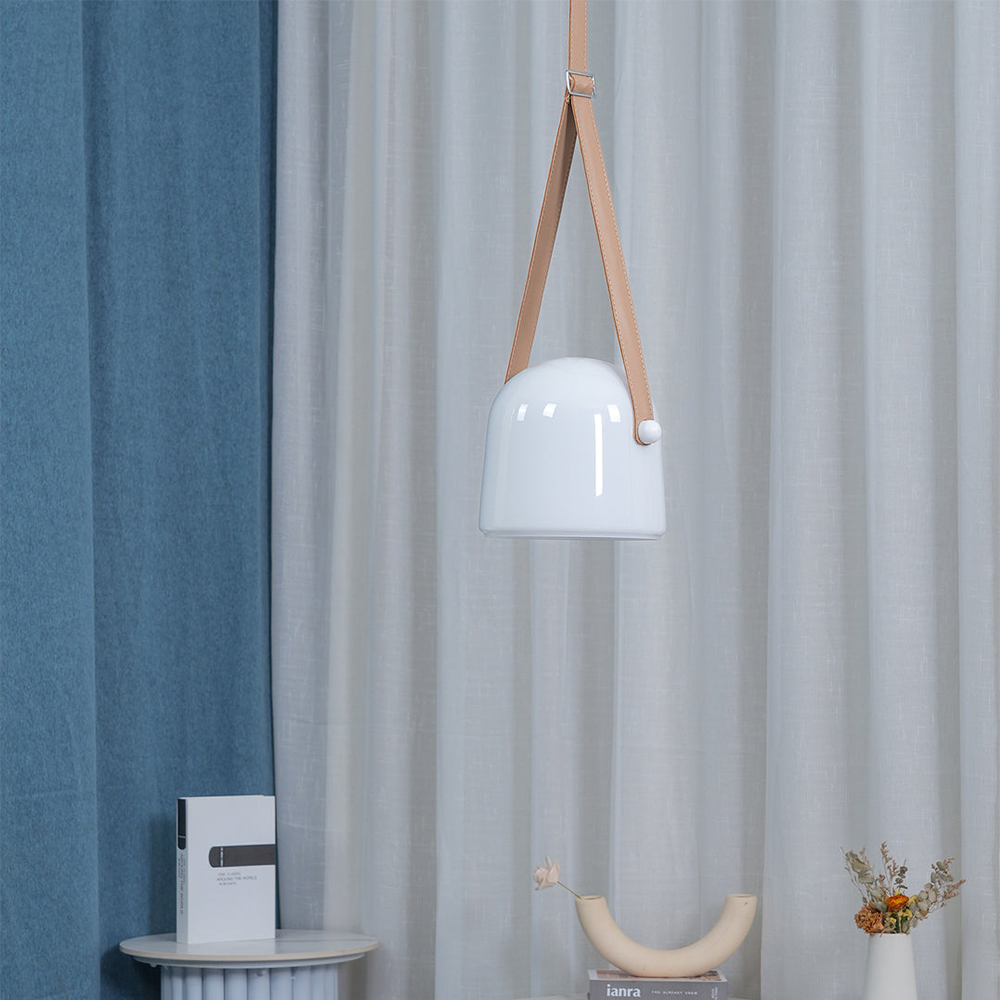 Close-up of opaque white glass shade with tan stitched strap, rectangular buckle and white side attachment