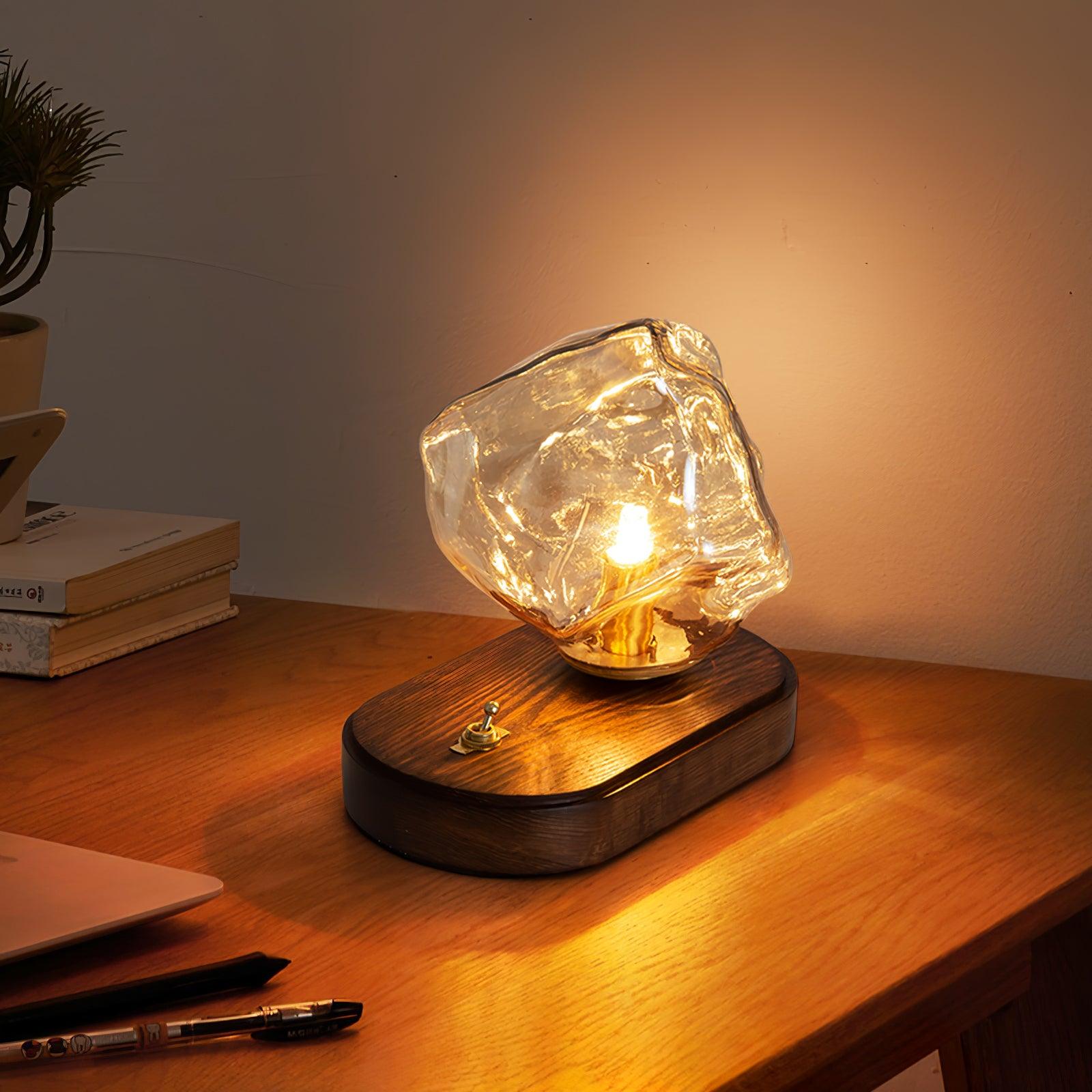 Wide desk view of the glowing Ice Stone lamp with books at left and pens in the foreground