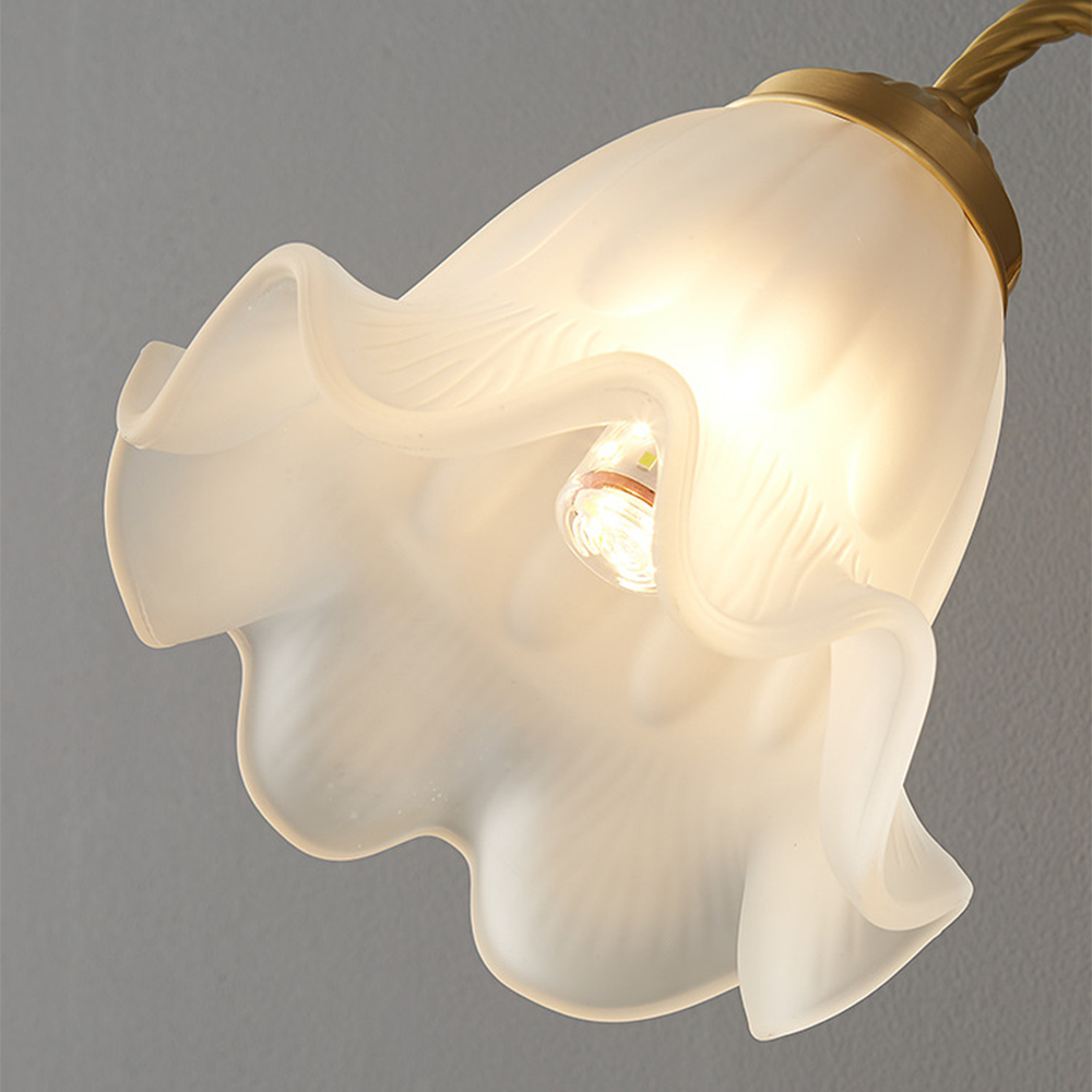 Angled underside of white scalloped shade showing lit cylindrical bulb, gold-tone collar and rope-textured arm