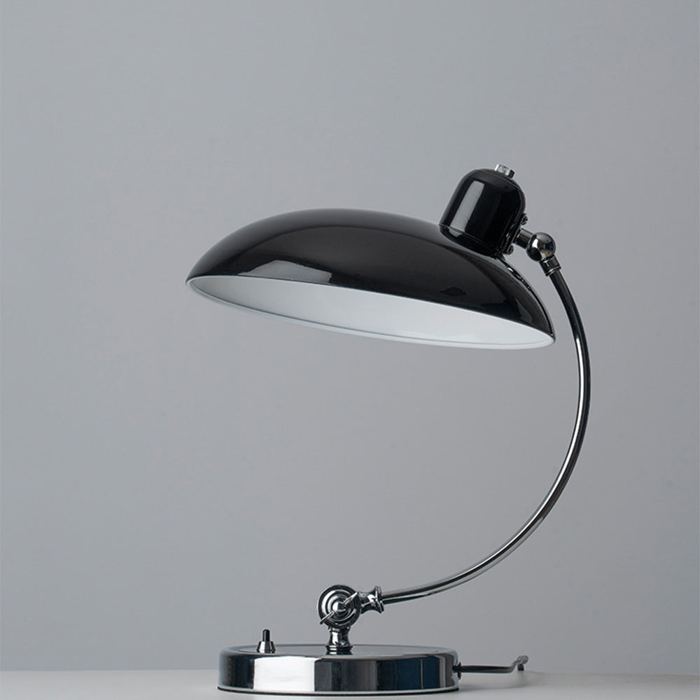 Unlit black dome table lamp with pale shade interior, reflective curved stem and round base