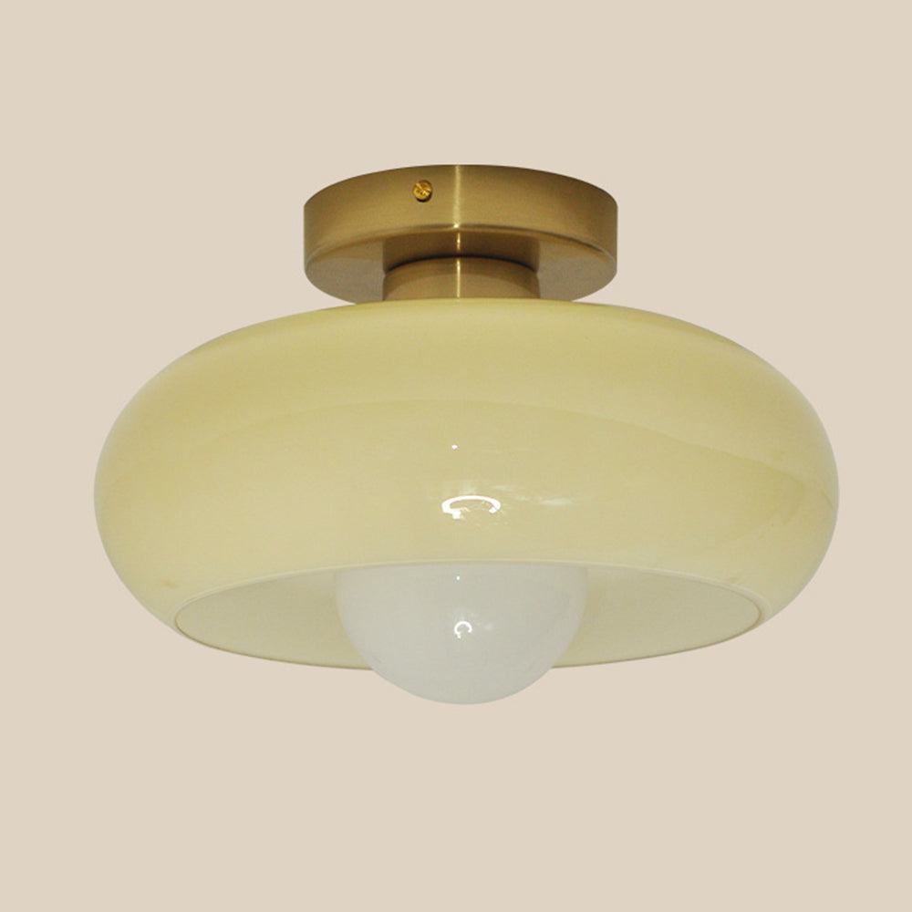 Cream glass semi-flush shade with gold ceiling fitting against a neutral background