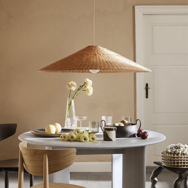 Natural Rattan cone pendant above a round dining table with flowers near a white door