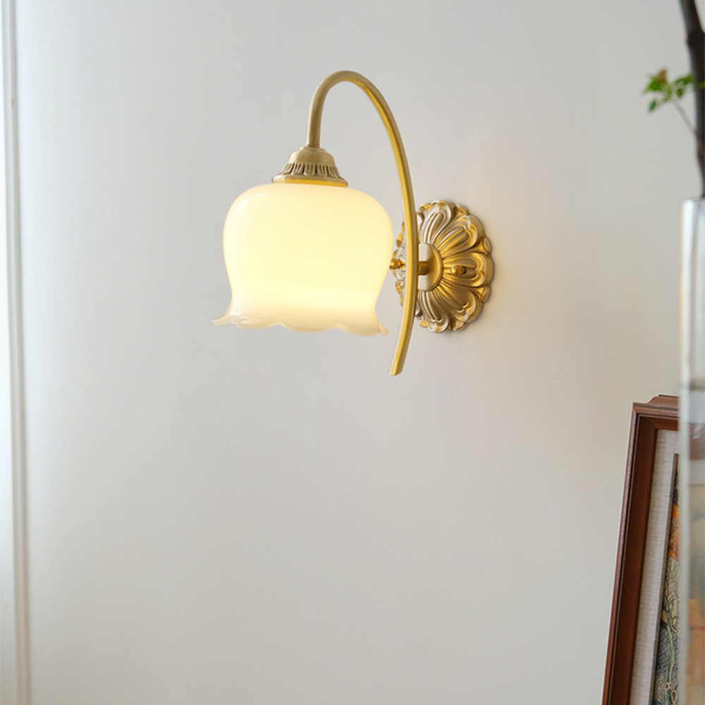White scalloped bell on curved arm near leaning framed picture and glass vase with green stem