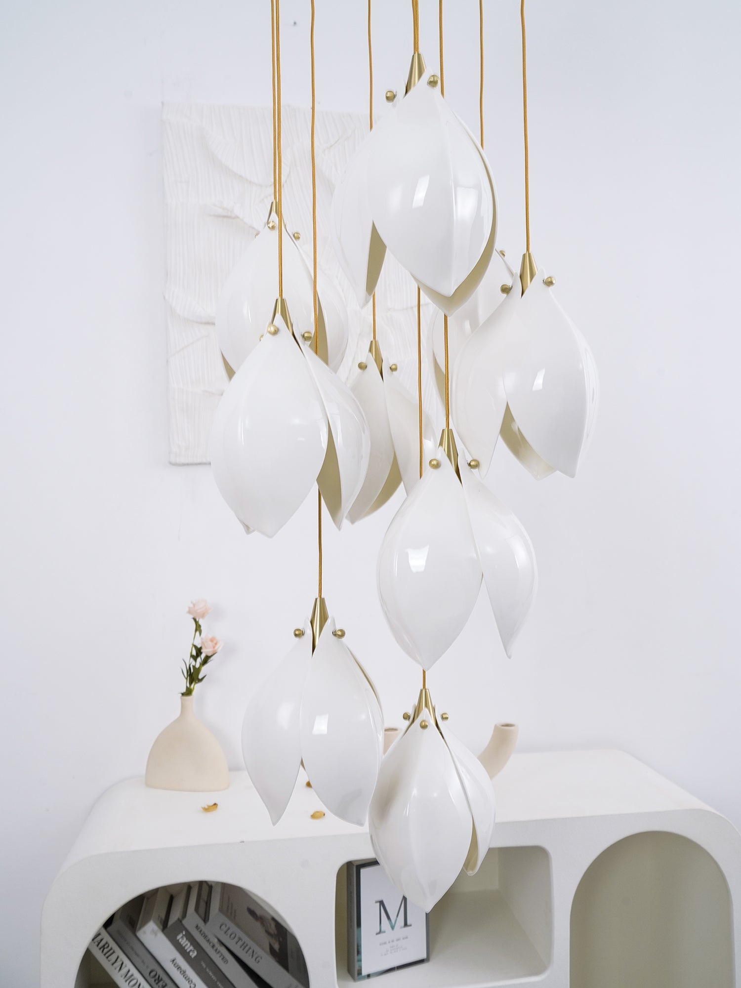 Glossy white curved petals and gold-tone fasteners before textured wall art