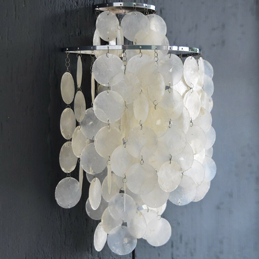 Closer front-oblique view of round shell discs hanging from reflective silver bands on dark wall