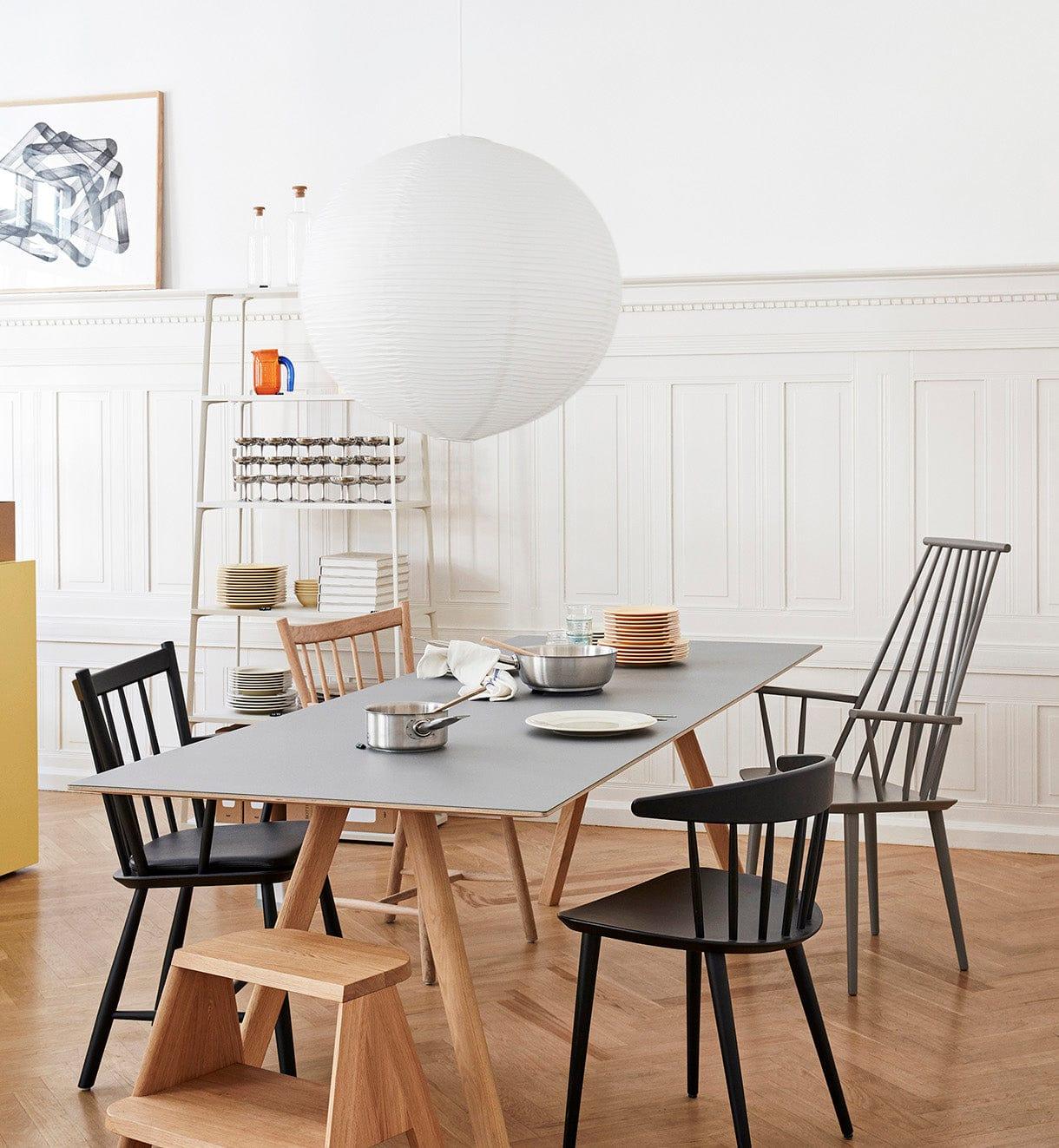 Paper globe above a grey dining table with wooden chairs, bowls, kitchen pans and a dish rack