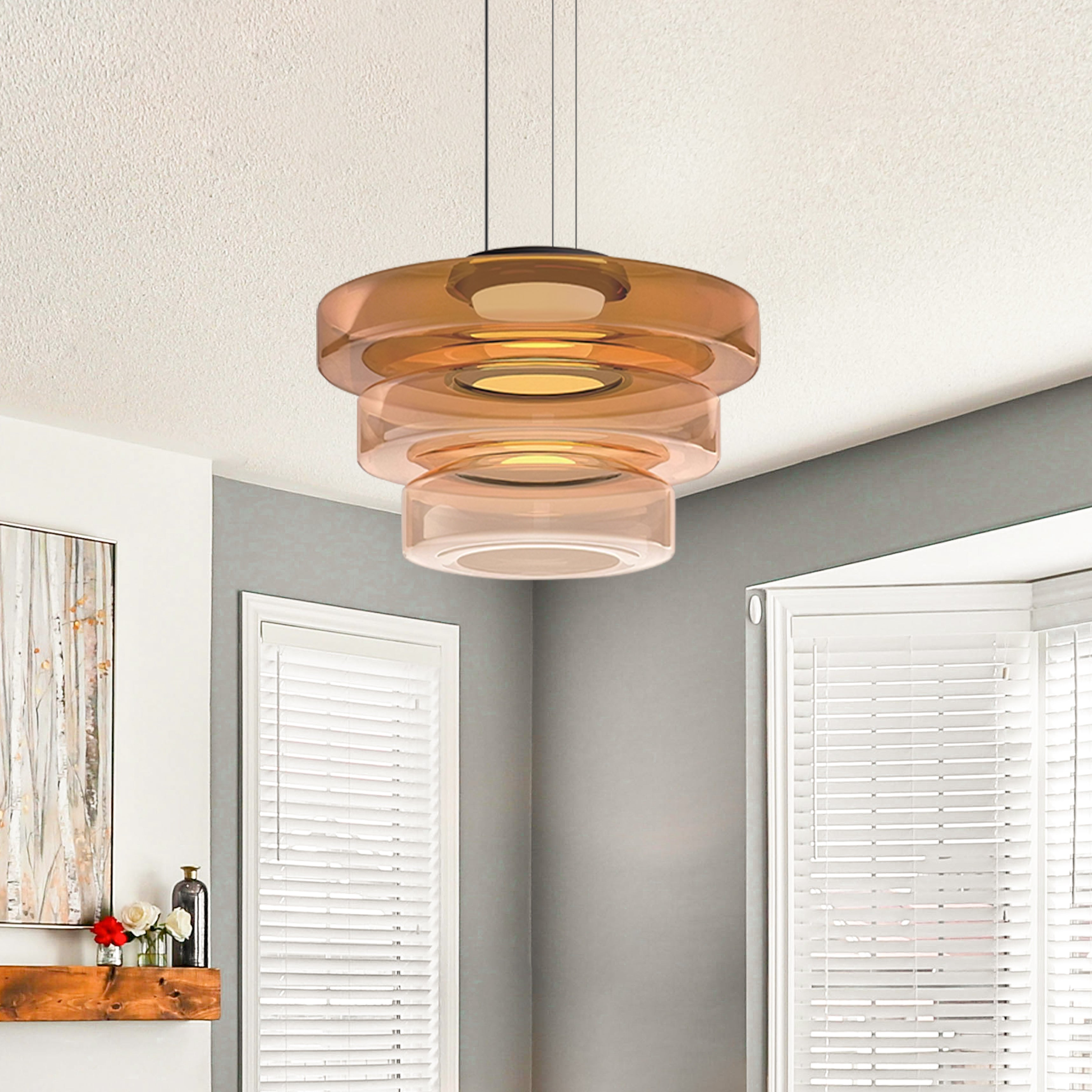 Amber three-tier glass pendant glowing beside two windows with white shutters