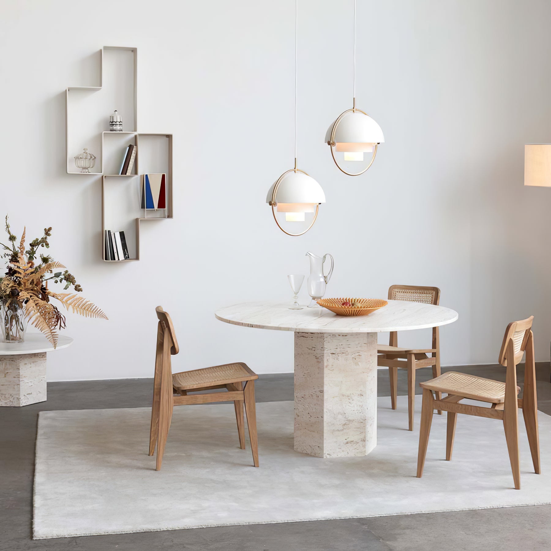 Two white ring pendants arranged above a round pedestal dining table.