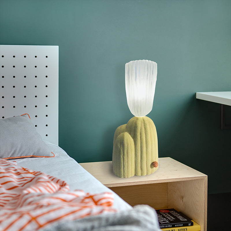 Cactus table lamp on a bedside cabinet against a green wall