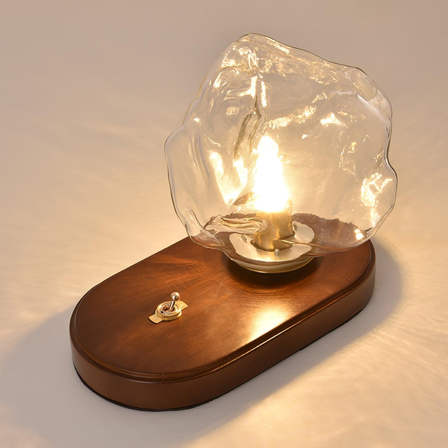 High angled close-up of the Ice Stone folded glass shade, oval wood base and gold-tone toggle