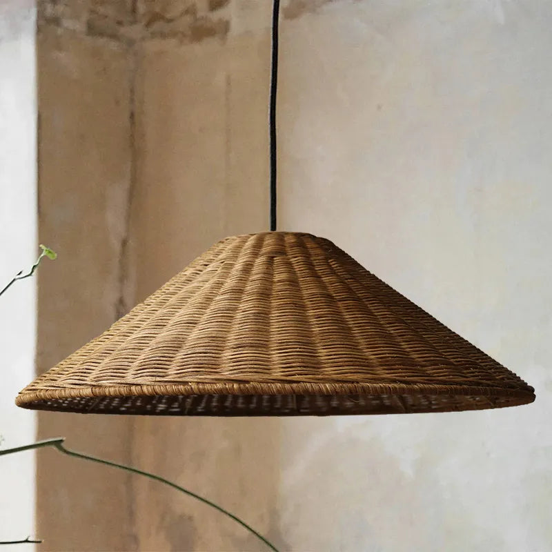 Close-up of an unlit Brown woven cone shade with wrapped rim against a warm textured wall